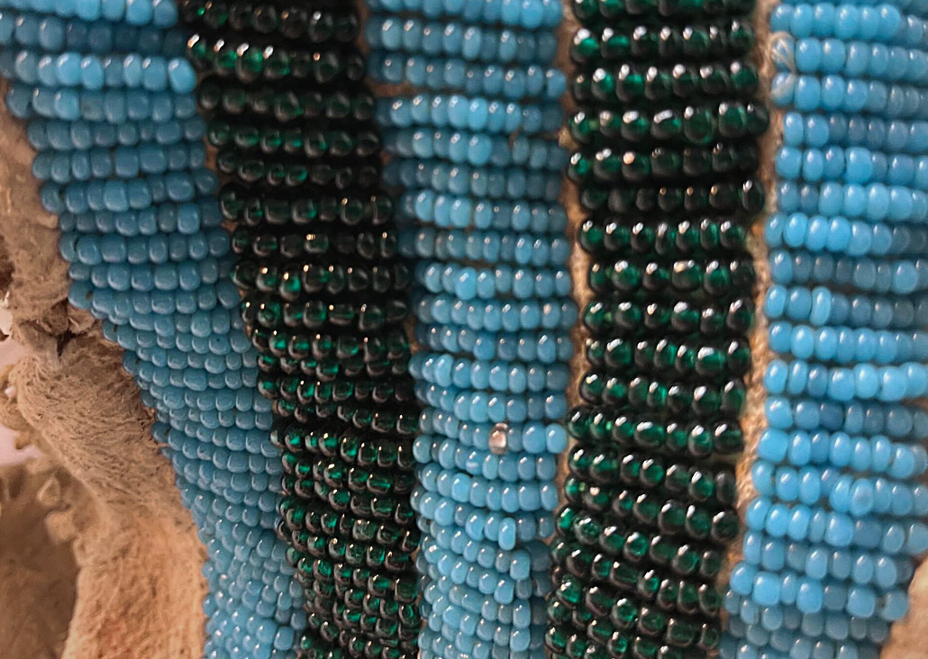 A detail of the blue and black beaded design on an animal hide garment.